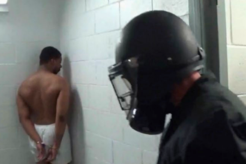 A prison guard looks at a handcuffed Ernastiaze Moore after he is allegedly sexually assaulted.