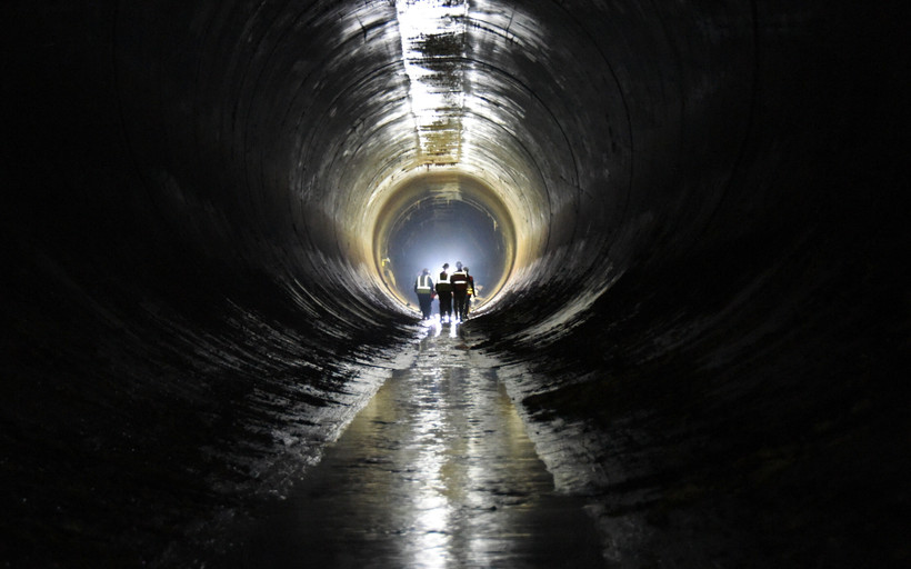 Workers walk inside of a New York City water tunnel.