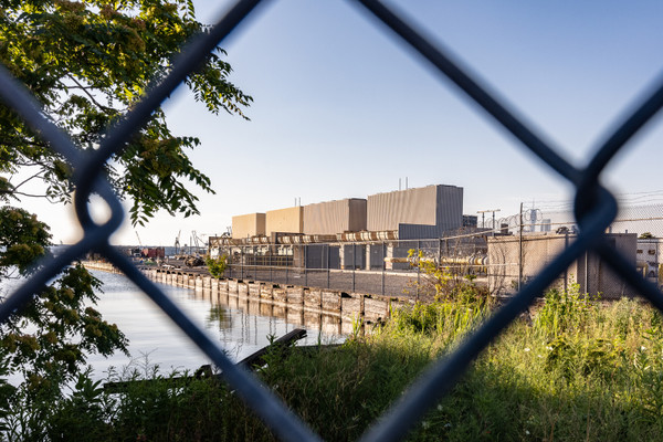 The Gowanus Generating Station in Brooklyn seen through a chain-link fence