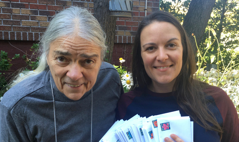 Maggie Ornstein, a young or middle-aged woman, stands to the right of her older mother. Maggie is holding several envelopes and the two are outside.