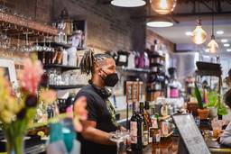 Masked barista stands behind counter