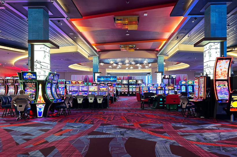 A mostly-empty floor of slot machines at Resorts World Catskills, with one gambler sitting off to the side.