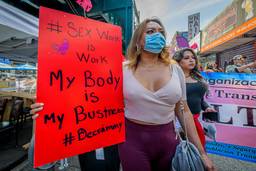 "Sex work is work / My body is my business / #Decrim" reads a large red sign held by a marcher