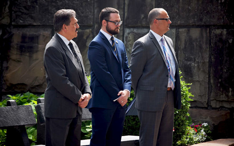 Three men in suits, including former acting prison commissioner Anthony Annucci and acting prison commissioner Daniel Martuscello III, stand at a memorial ceremony in Albany.