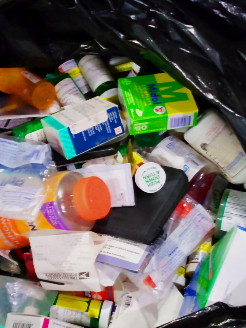 An open black trash bag shows an array of pharmaceutical products.
