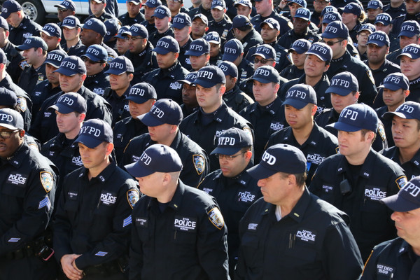 New York City Police Department members stand in a line wearing NYPD baseball caps.