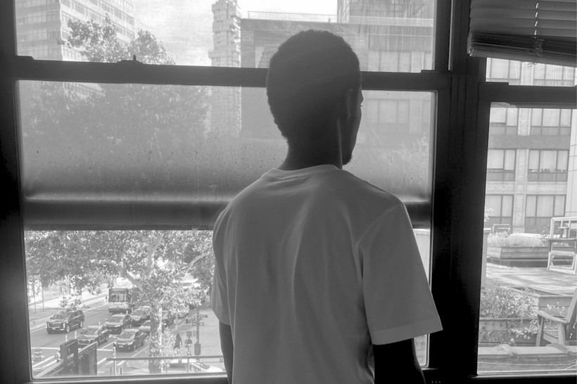 Theirno sits at a table, looking over his shoulder out of the window.