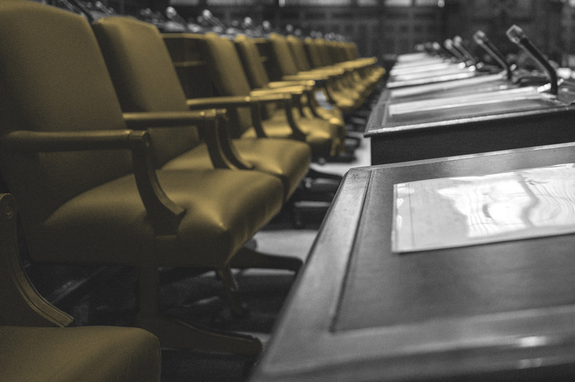 Image of a legislative chamber with many empty chairs.