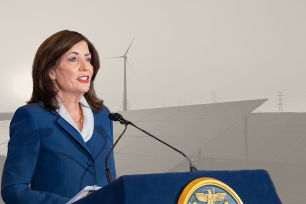 Photo montage showing NY Governor Kathy Hochul speaking on April 28 against a greyed-out backdrop of solar panels and a wind turbine.