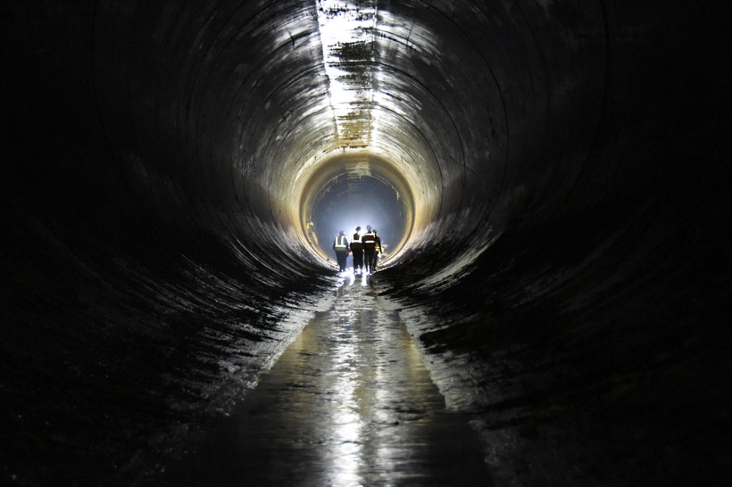 Workers walk inside of a New York City water tunnel.