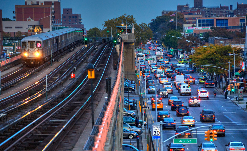 A New York City subway on the left, and highway traffic on the right.