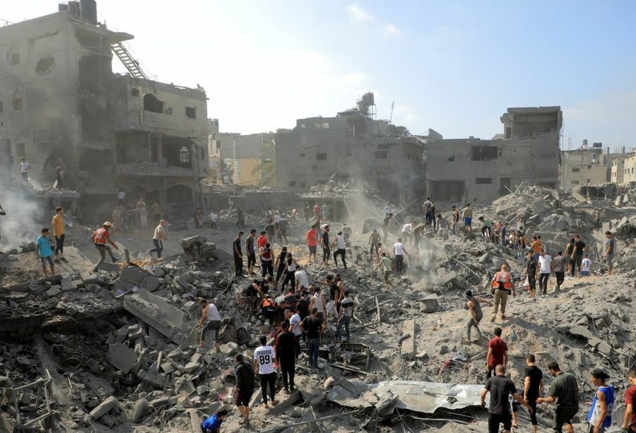 In a wide-angle photograph, people walk through a sea of rubble.