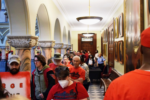 Rochester, NY residents dressed in red with the group Metro Justice wait at the city council in June.
