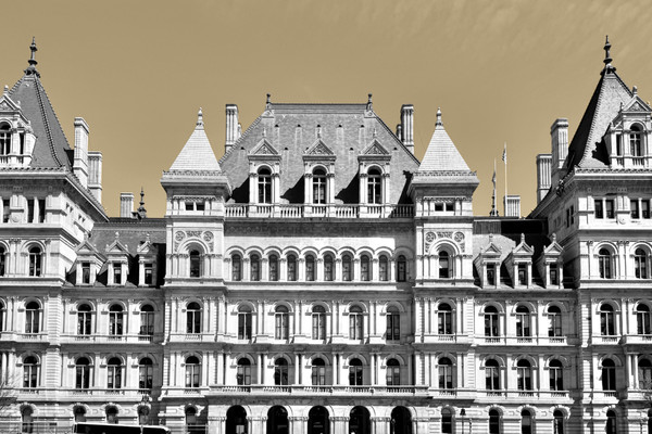 A black and white photo of the New York state Capitol Buildling over a yellow-tinted background.