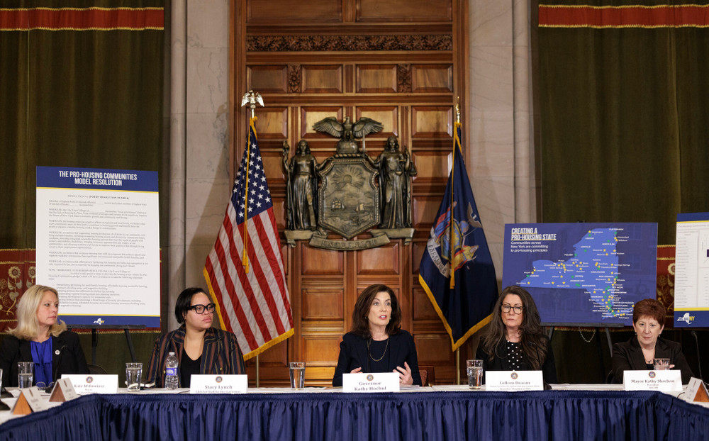New York Governor Kathy Hochul speaks on a panel for pro-housing communities with five other people in the Capitol.