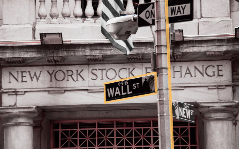 A photo illustration showing the New York Stock Exchange building and the street sign for Wall Street.