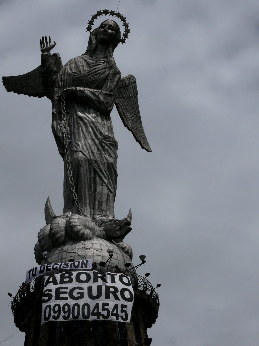 Pictured is a statue of the Virgin Mary in Quito, Ecuador, where in 2008, abortion rights activists hung a large white banner reading "Aborto Seguro" which means safe abortion.