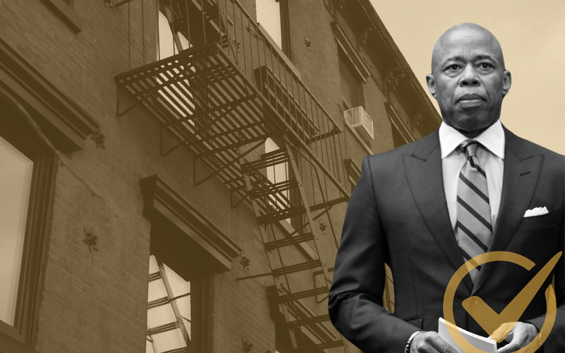 Mayor Eric Adams standing in front of an apartment building.
