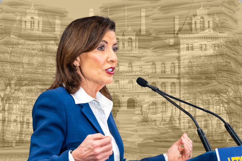 A photo collage of Governor Kathy Hochul over a yellow-tinted photo of many tall stacks of paper superimposed onto the New York state Capitol.