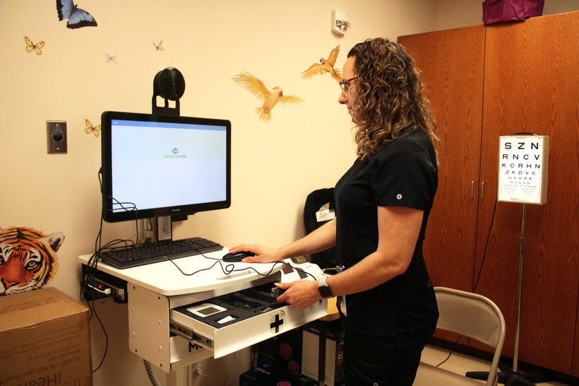 A nurse stands at a computer in a school nurse's office