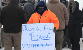 A worker holding up a sign that says "Just a few "Rogue" NYSCOPBA Members"