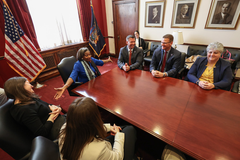 New York state Senate Majority Leader Andrea Stewart-Cousins sits at the head of a table with her arms spread wide.
