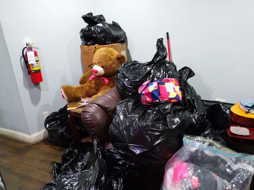 A pile of trash bags in an apartment with a teddy bear on top.