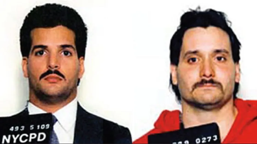In a mugshot of two men, the one on the left wears a suit and tie; the one of the right wears a red hoodie.