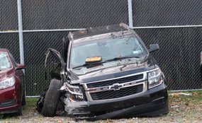 A car with the right side destroyed sits in a lot.