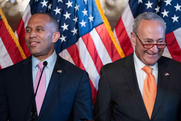 House Minority Leader Hakeem Jeffries and Senate Majority Leader Chuck Schumer, Democrats of New York, smile in front of american flags