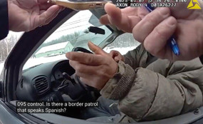 A screenshot from a police body camera shows a person in a car, his face obscured by the officer's hands holding a phone. The caption shows the officer saying "Is there a border patrol that speaks Spanish?"