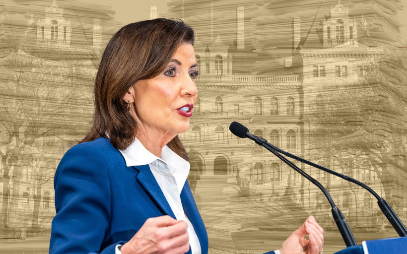 A photo collage of Governor Kathy Hochul over a yellow-tinted photo of many tall stacks of paper superimposed onto the New York state Capitol.