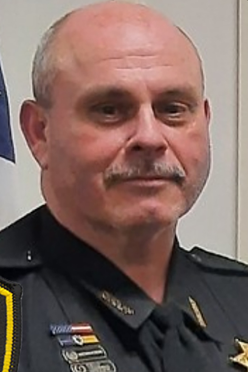 A middle-aged white bald man with a gray mustache in a police uniform.