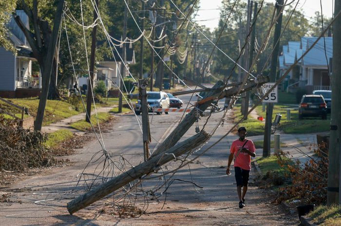 A person walks past a tangle of downed power lines blocking a road