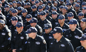 New York City Police Department members stand in a line wearing NYPD baseball caps.
