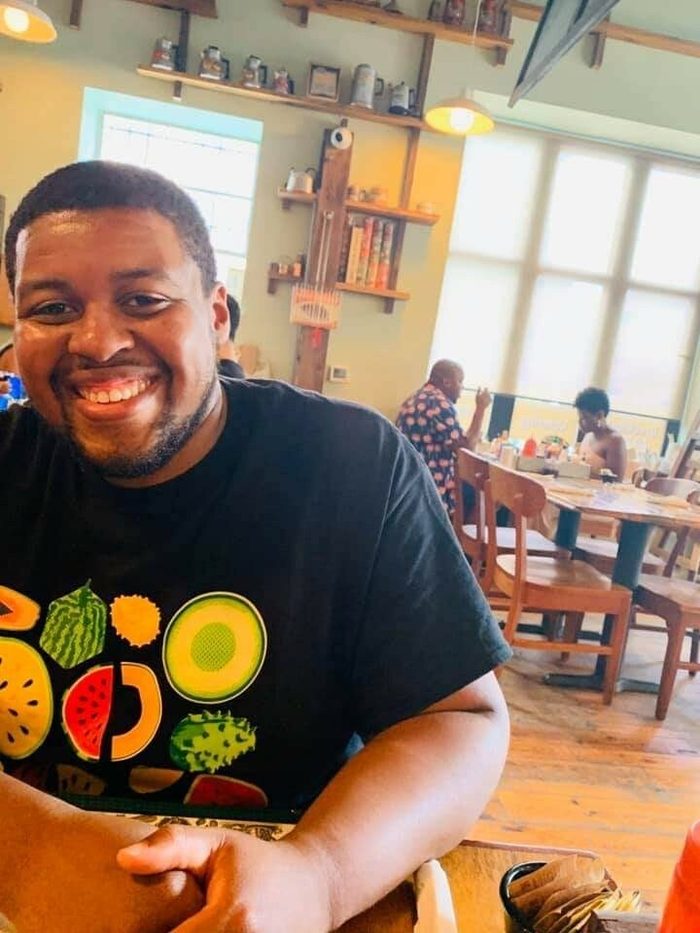 Smiling man in foreground with table behind him