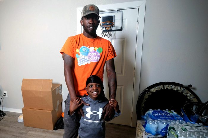 Man wearing a cap and orange shirt with young boy who is smiling