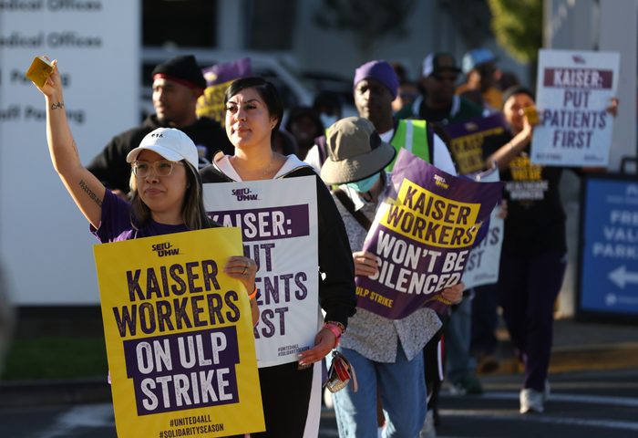 Kaiser Permanente workers on strike in Vallejo, Calif., hold yellow, white and purple signs reading, "Kaiser Workers On ULP Strike."