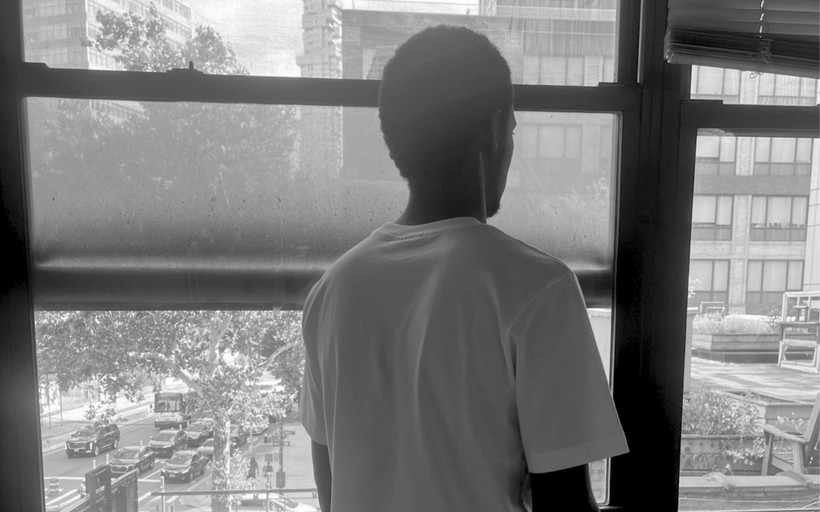 Theirno sits at a table, looking over his shoulder out of the window.