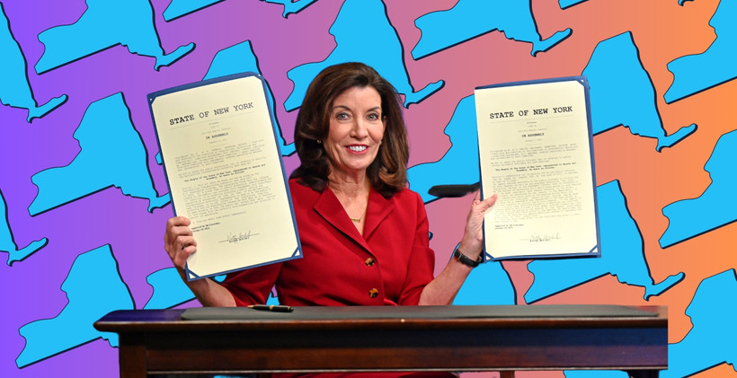 Governor Kathy Hochul holds two signed bills, superimposed over a background showing the state of New York.