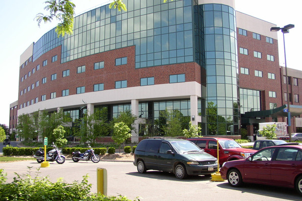 Exterior of a hospital with cars and motorcycles parked in front