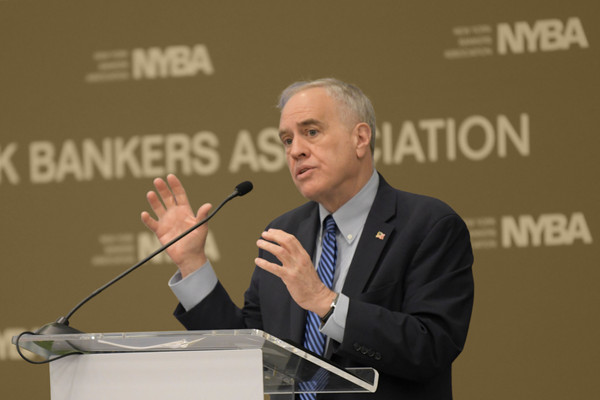 Comptroller Tom DiNapoli speaks at a podium, gesticulating with his hands.