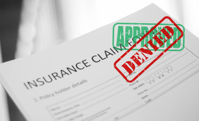 An insurance claim has first been stamped "approved," but then stamped "denied."