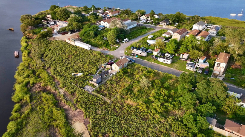 Remnants of the destruction of 2012’s Superstorm Sandy, including debris and a scuttled boat, still lay beside Baba Ndanani’s home on Edgemere’s bayside peninsula. Ten years after city officials pledged to raise Edgemere’s bayside shoreline, the project has yet to break ground.